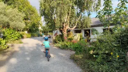 Accueil 3 Un enfant fait du velo dans une allee verdoyante du camping