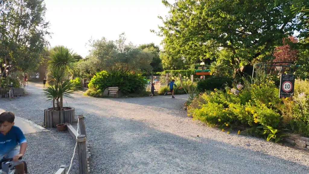 Enfant jouant en toute sécurité dans une allée verdoyante et arborée du Camping du Pouldu à Clohars-Carnoët