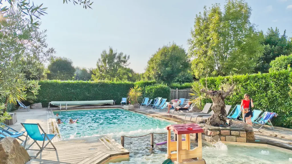 Piscine chauffée et paysagée éclairée à la tombée de la nuit au Camping du Pouldu à Clohars-Carnoët.